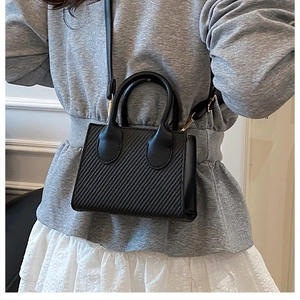 Dettaglio della mini borsa nera a tracolla con texture diagonale e fibbia dorata