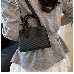 Dettaglio mini borsa tote nera con trama intrecciata diagonale e doppia opzione di trasporto