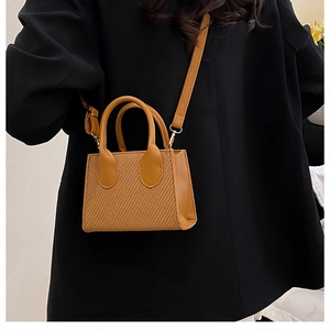 Vista dettagliata della borsa marrone intrecciata abbinata a un blazer nero in stile minimal