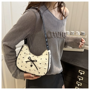 Detail of seersucker underarm bag with bow print, silver heart pendant and leather strap
