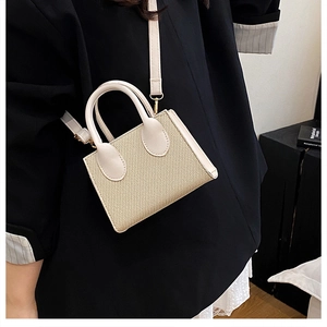 Dettaglio di una borsa a tracolla intrecciata crema con cinturini in pelle su un modello