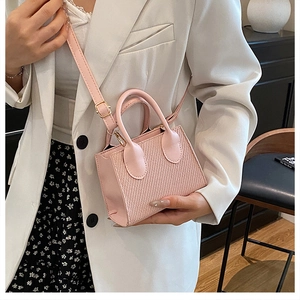 Dettaglio della borsa rosa intrecciata con fibbie dorate abbinata a un blazer bianco