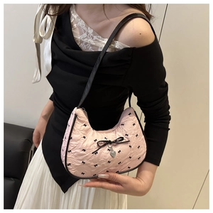 Detail of pink crescent bag with black bow prints, ribbon decoration and silver heart charm