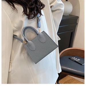 Dettaglio mini borsa grigio chiaro testurizzata con finiture dorate e tracolla sottile