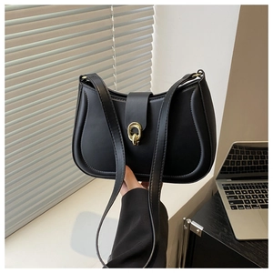 Detail of a black crescent shoulder bag featuring a prominent gold chain metal buckle