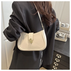 Close-up of cream leather underarm bag with elegant gold-tone double ring buckle