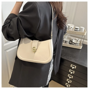 Detail of cream half-moon underarm bag with gold metal twist lock and slim shoulder strap