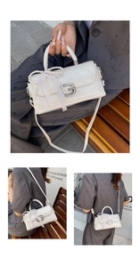 Detail of cream leather crossbody bag with pearl charms, lace bow, and logo buckle