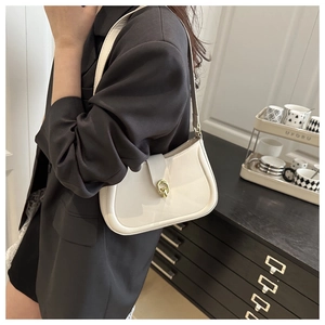 Detail of a creamy white leather underarm bag featuring a golden circular metal buckle clasp