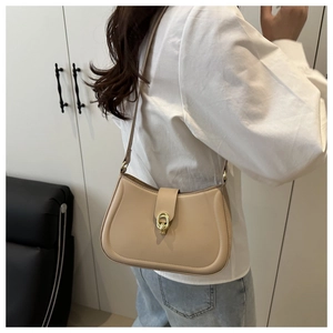 Detail of apricot faux leather hobo bag featuring a round silhouette and gold horseshoe buckle