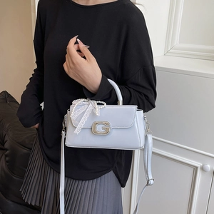 Detail of light blue patent leather handbag with sparkling G buckle and pearl strap