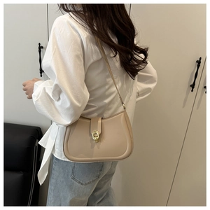 Beige underarm bag with gold chain hardware decoration worn by model in side profile