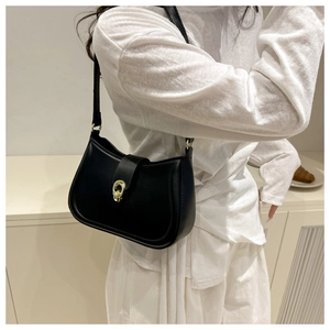 Detail of minimalist black semi-moon underarm bag with elegant gold twist-lock closure