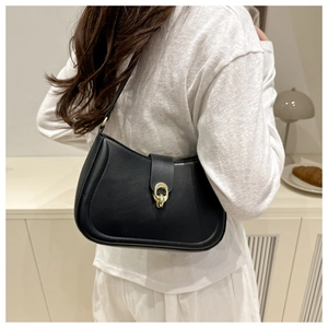 Close-up of black matte leather shoulder bag with gold interlocking metal buckle on white