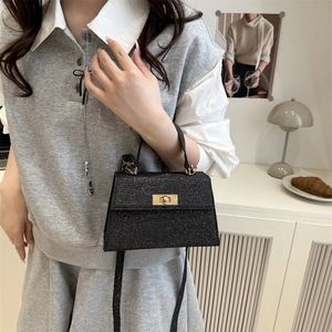Glittery black mini top handle bag with gold turn-lock and adjustable shoulder strap