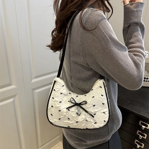 Borsa hobo trapuntata bianca con fiocchi neri e ciondolo a cuore su modella