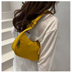 Side view of a bright yellow crescent shoulder bag with branded tag and zipper detail