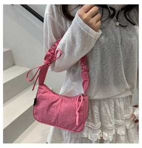 Pink pleated shoulder bag with knotted strap detail styled on white summer outfit