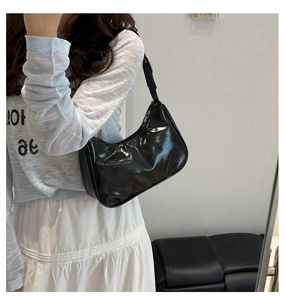 Detailed side view of glossy black faux leather crescent hobo bag with silver zipper