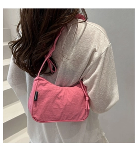 Detail of pink nylon crescent bag featuring side drawstring knot and logo tag texture