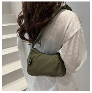 Olive green nylon underarm bag with pleated strap and side logo detail shown on shoulder