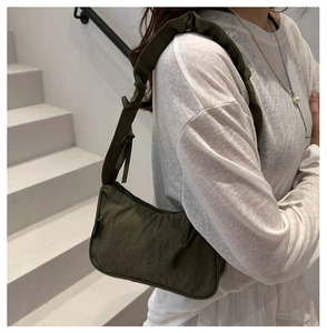 Olive green nylon shoulder bag with ruffled strap detail shown on a model