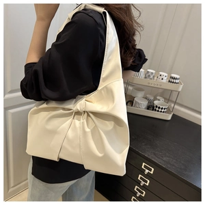 Close-up of cream white tote bag featuring a large decorative bow and matte leather finish