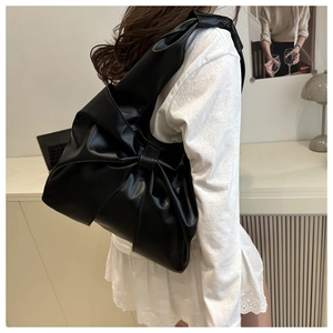 Detailed view of the large bow-knot pleats and leather texture on the black tote bag