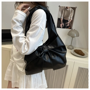Detail of the oversized leather bow and premium PU texture on the black shoulder bag