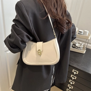 Chic beige hobo bag with golden buckle buckle shown as a stylish shoulder bag on a model