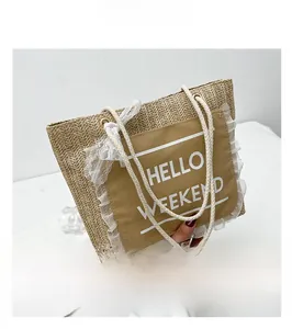 Detail of woven straw tote bag featuring white lace trim and Hello Weekend canvas pocket