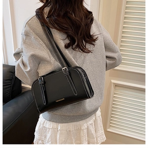 Detail of a black leather underarm bag with white contrast stitching and silver hardware