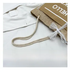 Detail of woven straw tote bag featuring rope handles and white lace bow decoration