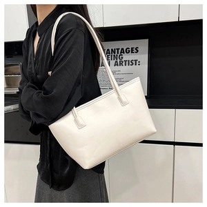 Detail of minimalist off-white leather tote bag showing reinforced straps and matte texture