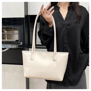 Detail shot of a soft cream tote bag with long shoulder straps and smooth PU leather