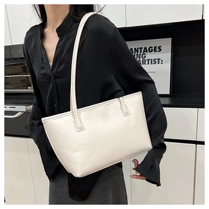 Detail of minimalist cream PU leather tote bag with slender straps in a modern setting