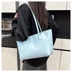 Minimalist light blue tote bag shown from a side perspective worn by a model