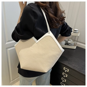 Detail of hand-woven straw tote bag with white leather trim and V-shaped opening design