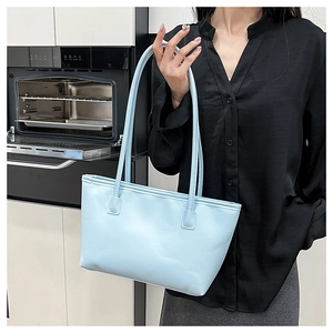 Side view of a light blue minimalist tote bag worn by a model in a modern kitchen setting