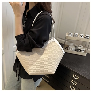 Close-up of beige woven tote bag with white leather trim and slim shoulder straps