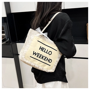 Close-up of woven straw tote bag with Hello Weekend patch and white lace details