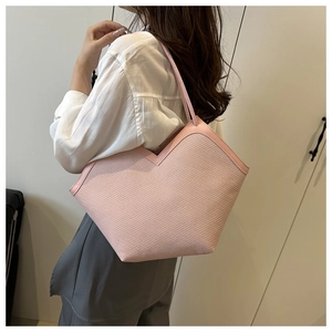 Detail of pink woven tote bag showing V-cut edge and slender shoulder strap texture