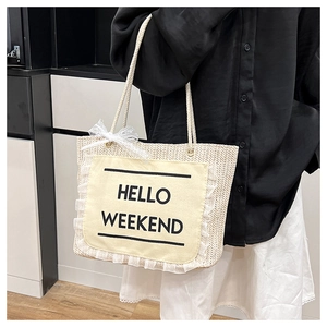 Detail of woven straw tote bag featuring Hello Weekend print and lace bow decoration