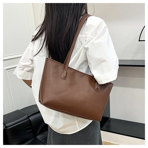 Side view of a vintage dark brown leather tote bag worn by a model in a minimal room
