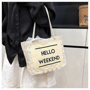 Detail of straw tote bag with lace trim and Hello Weekend slogan on canvas patch