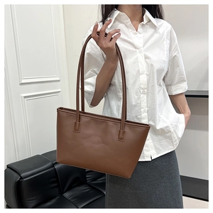 Minimalist dark brown tote bag on model's shoulder showing urban commute fashion style