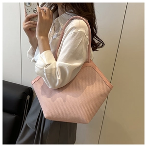 Detail of pink straw tote bag with fine woven texture and long leather shoulder straps