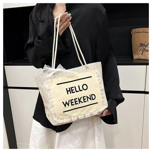 Detail of woven straw tote bag with Hello Weekend patch and white lace trimming