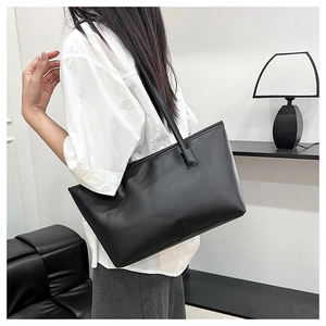 Close-up of black matte PU leather tote bag worn by a model in a minimalist setting