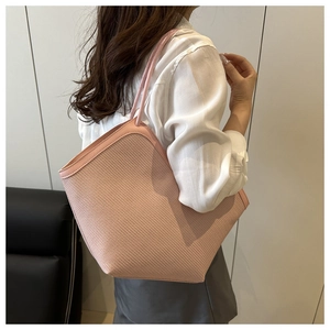 Detailed side view of a large pink woven tote bag showing texture and shoulder strap fit